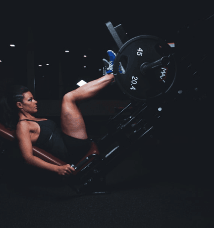 Mulher realizando exercício de pernas em nossa máquina de academia